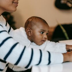 Black mother at her laptop holding a baby