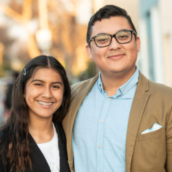 Smiling Hispanic young man posing with his sister looking at the camera.