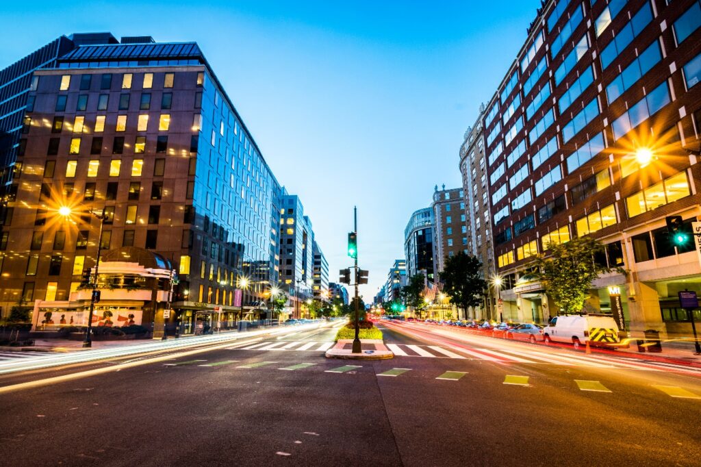 A street with buildings and cars in the background Description automatically generated