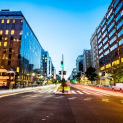 A street with buildings and cars in the background Description automatically generated