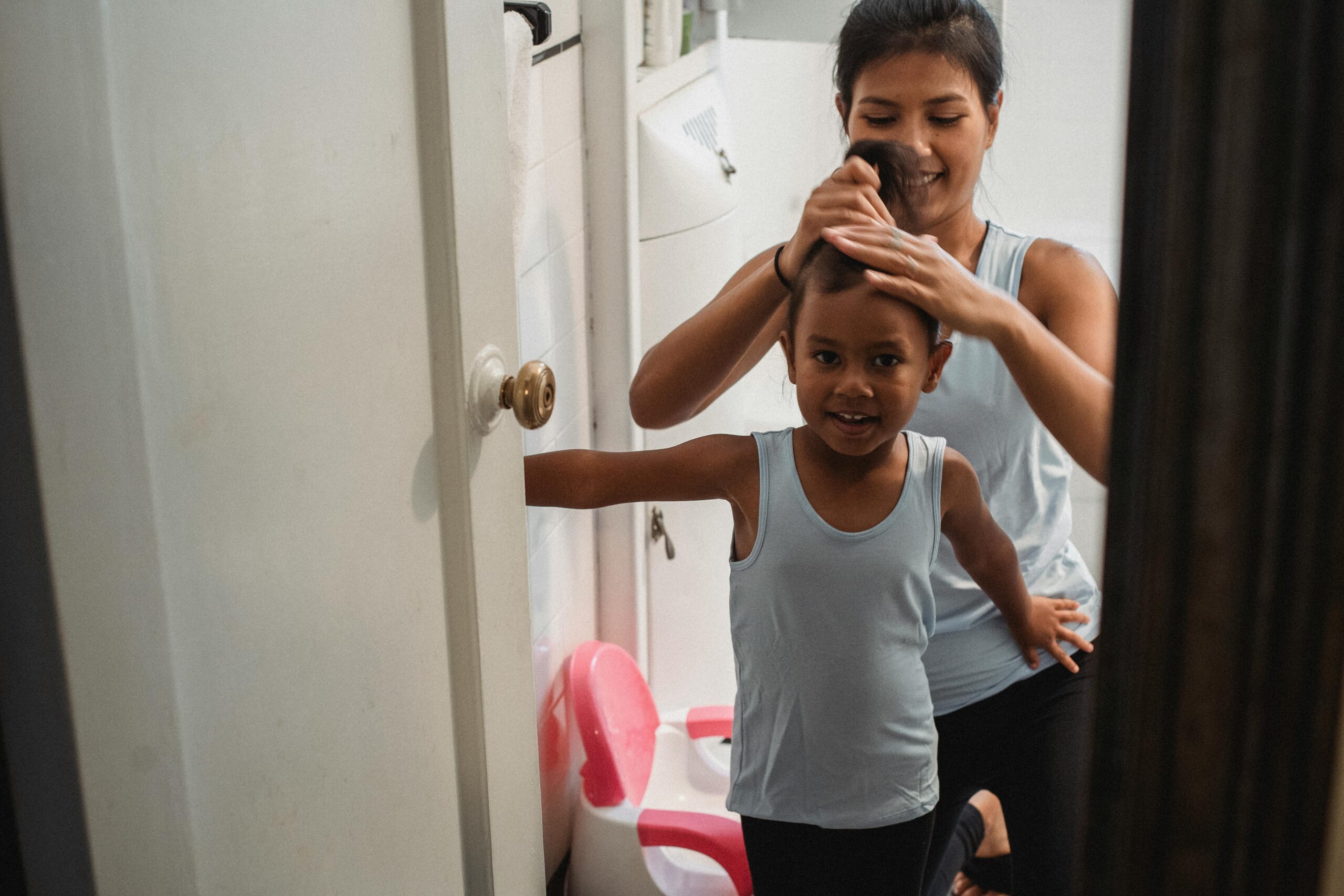 Woman tying child's hair into a ponytail
