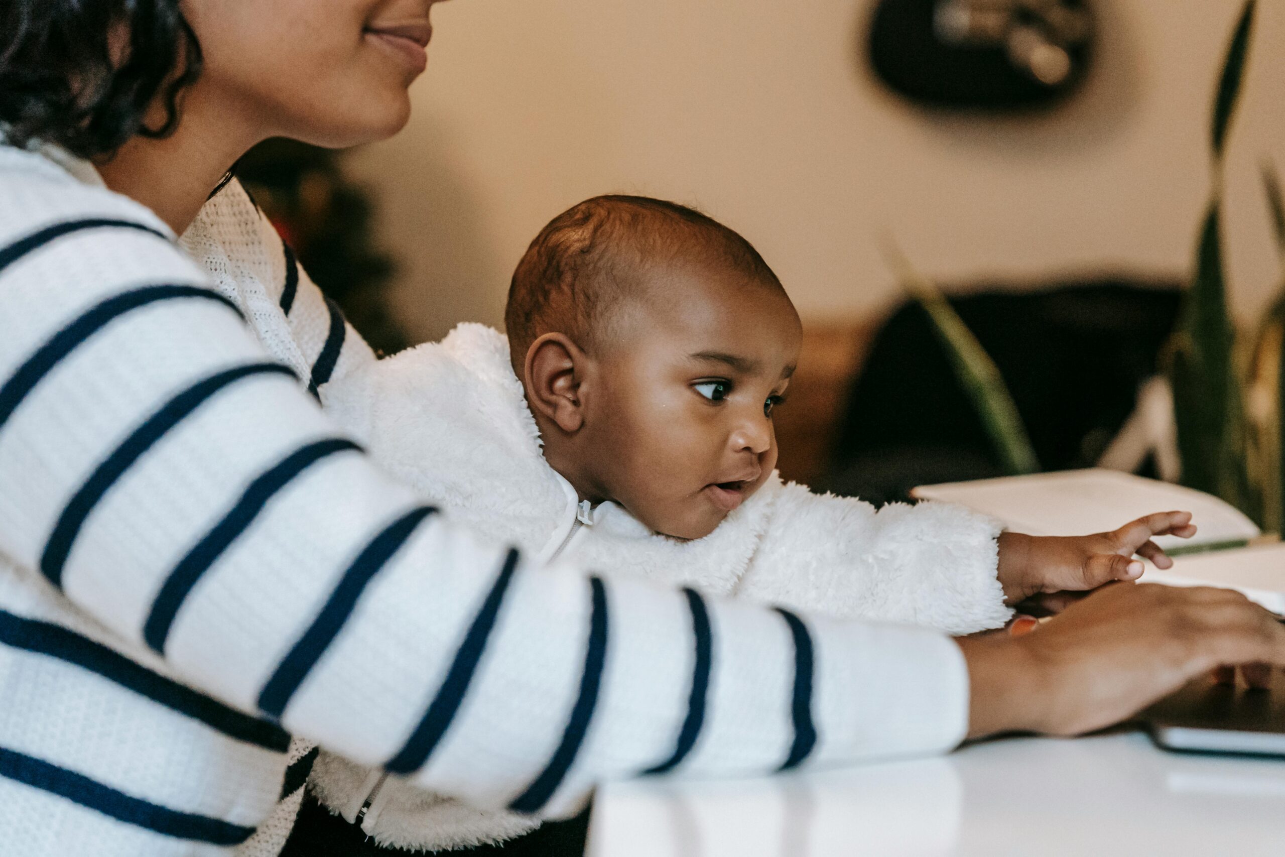 Black mother at her laptop holding a baby