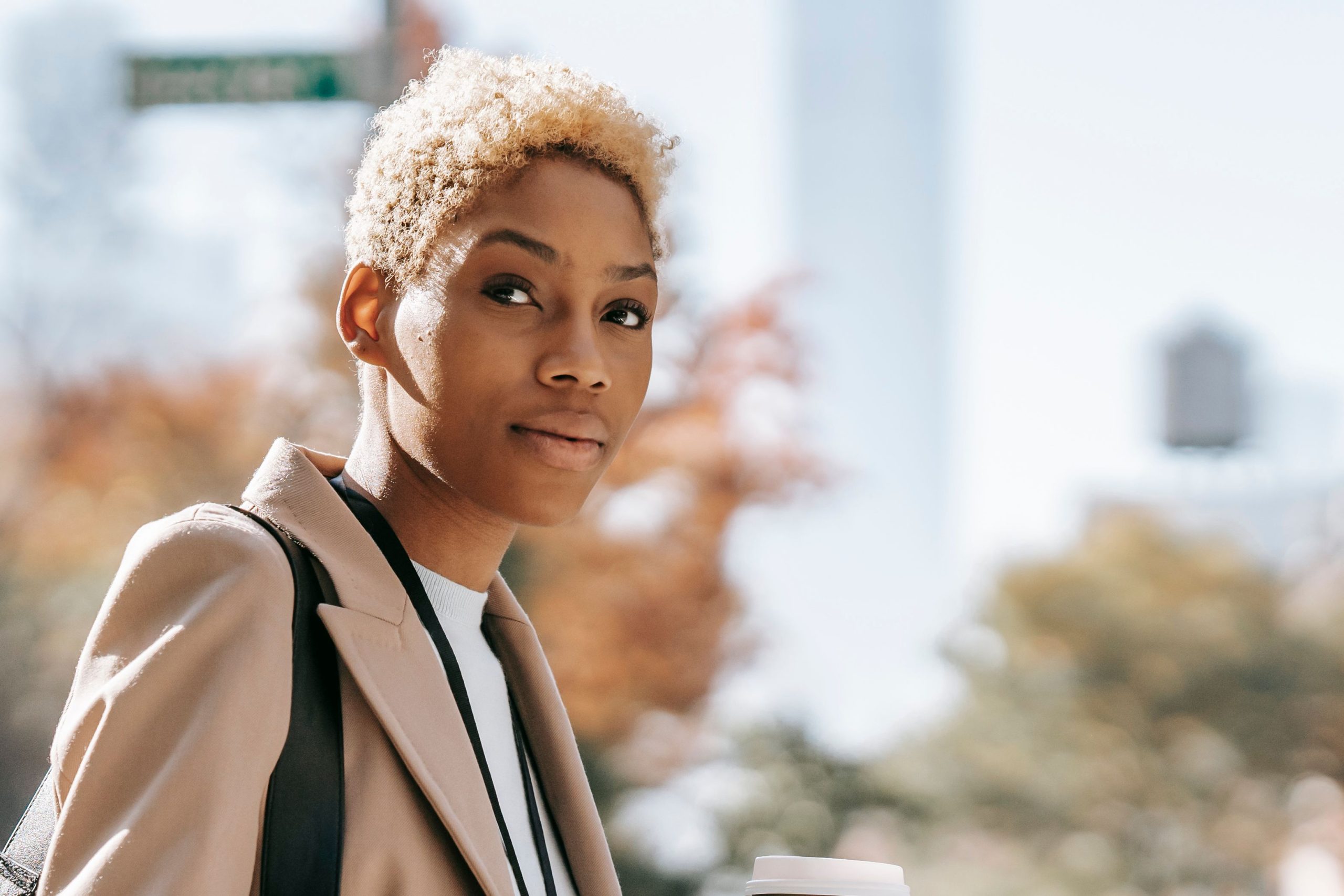 Black woman with blonde hair and wearing a blazer looks at camera.